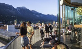 Acht Personen stehen oder sitzen auf der Dachterrasse des 360 Grad Cafes mit Blick auf Innsbruck