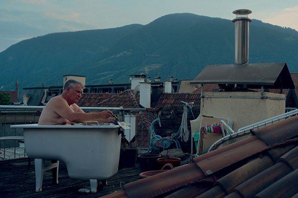 Schönweger in Badewanne auf Hausdach bei der Arbeit