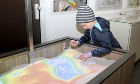 Kind an einem interaktiven Ausstellungsobjekt im Geologischen Museum