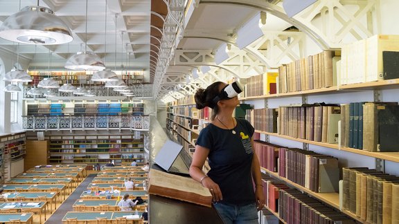 Frau die mit VR Brille in Bibliothek ist.