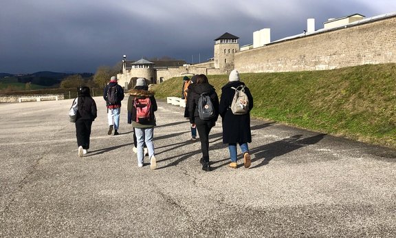 Mehrere Personen sind von hinten auf der heutigen Gedenkstätte Mauthausen zu sehen.