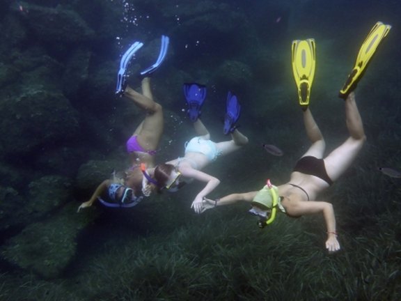 three students snorkeling together under water