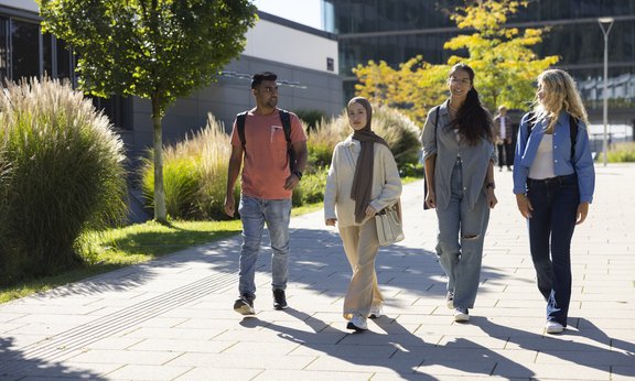 vier Studierende gehen gemeinsam über den Campus Technik und sprechen miteinander