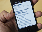 Hand hält Smartphone, auf dem Smartphone ist Mobilversion von LFU:online geöffnet