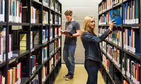 zwei Studierende stehen in der Bibliothek