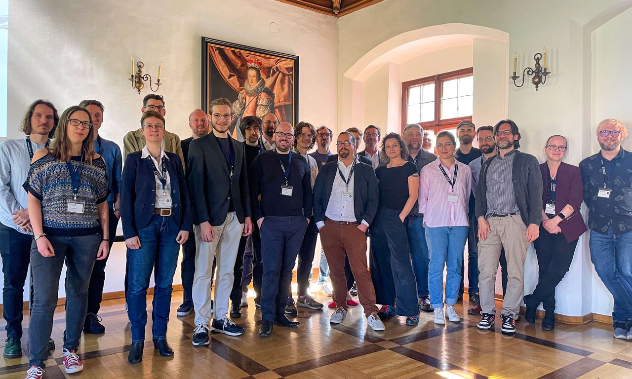 Gruppenfoto von über 20 Personen im vorderen Bereich des Claudiasaals.