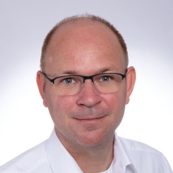 Porträtfot von Jörg Lücke in Hemd und mit Brille