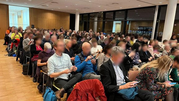 View into the audience, faces are blurred for data privacy reasons