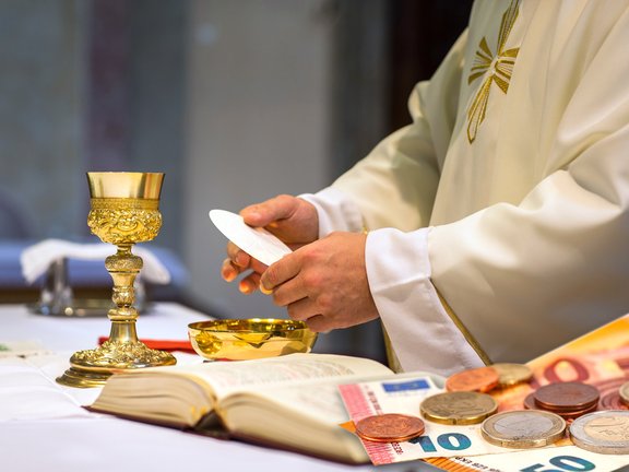 Das Bild zeigt eine Eucharistiefeier, Geldscheine und Münzen.