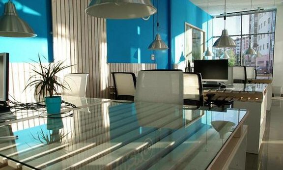 Schönes helles und sauberes Büro mit großem Fenster und einer hellblauen Wandfarbe.