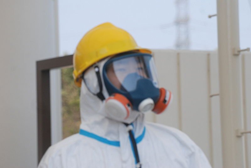 Bild: Ein Wachmann im Schutzanzug mit Atemschutz am Eingang zum Kraftwerk, aufgenommen am 13. April 2011.