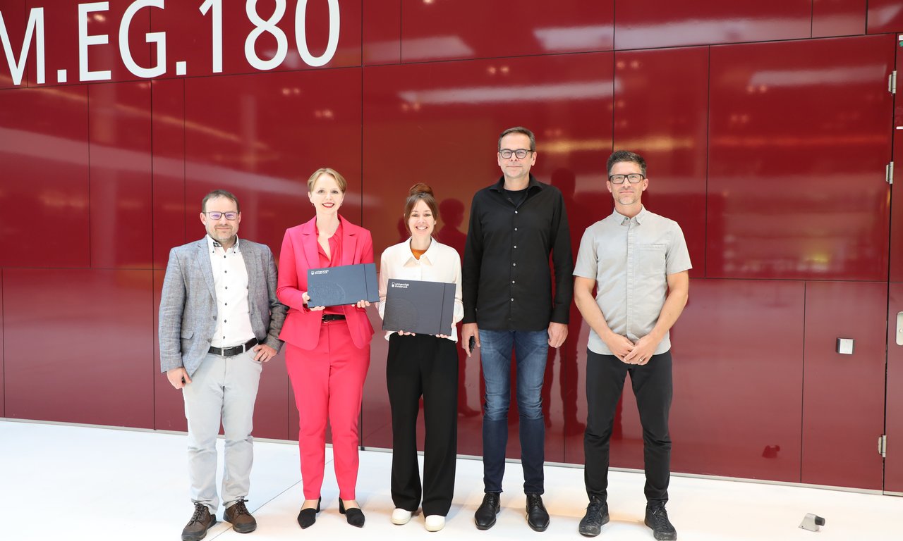 Drei Männer und zwei Frauen stehen für ein Gruppenfoto nebeneinander, die Frauen halten Urkunden.