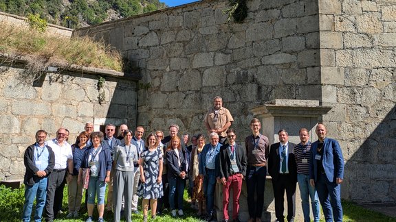 Gruppenaufnahme Tagungs-Teilnehmende bei strahlendem Sonnenschein im Innenhof des Talwerkes auf der Festung Franzensfeste