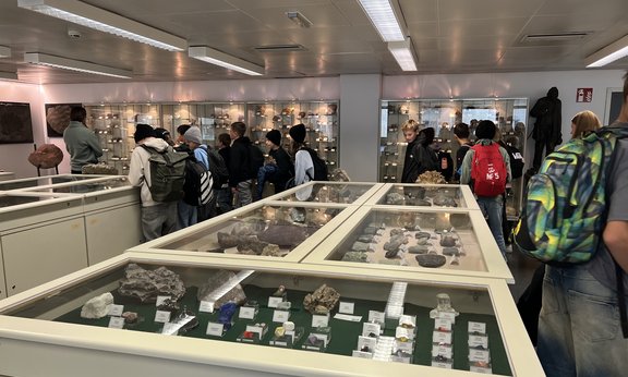 Schulklasse wird durch die Vitrinen der Schausammlung mit Fossilien, Mineralen und Gesteinen geführt