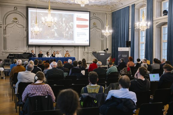 Besucher:innen in Hörsaal, von hinten aufgenommen