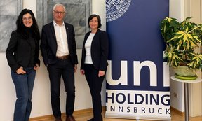 Gruppenfoto mit drei Personen und dem Logo der Uni-Holding.
