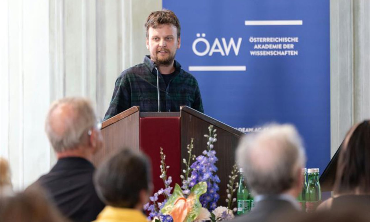 Der Preisträger an einem Rednerpult, im Vordergrund das Publikum