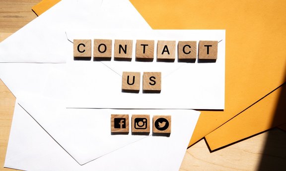 "Contact us" und Social Media Icons auf Holzlettern