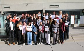 Gruppenfoto der Absolvent:innen, sie halten ihre Zertifikate in der Hand.