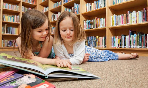Zwei kleine Mädchen die zusammen etwas lesen.