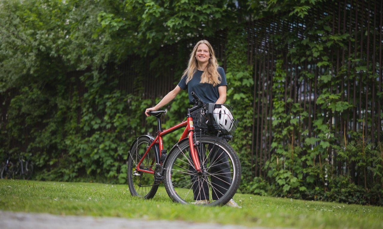 Junge Frau mit einem Fahrrad im Freien stehend.