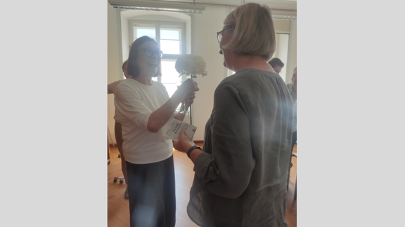 Zu sehen sind die Mitglieder des Instituts beim Sommerumtrunk. Blumen werden überreicht.