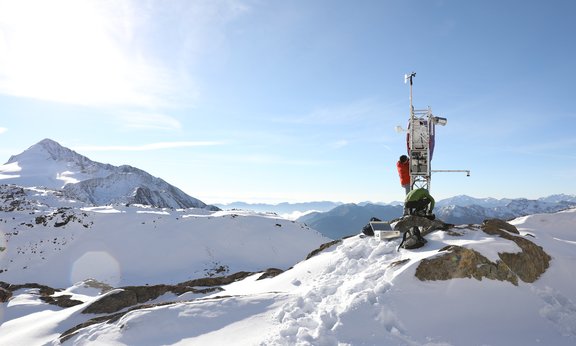 Zwei Wissenschaftler warten ein Messgerät auf einem verschneiten Berggipfel