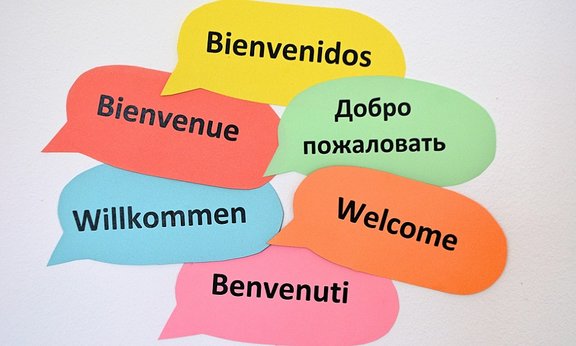 Bunte Sprechblasen mit dem Wort "Willkommen" in verschiedenen Sprachen