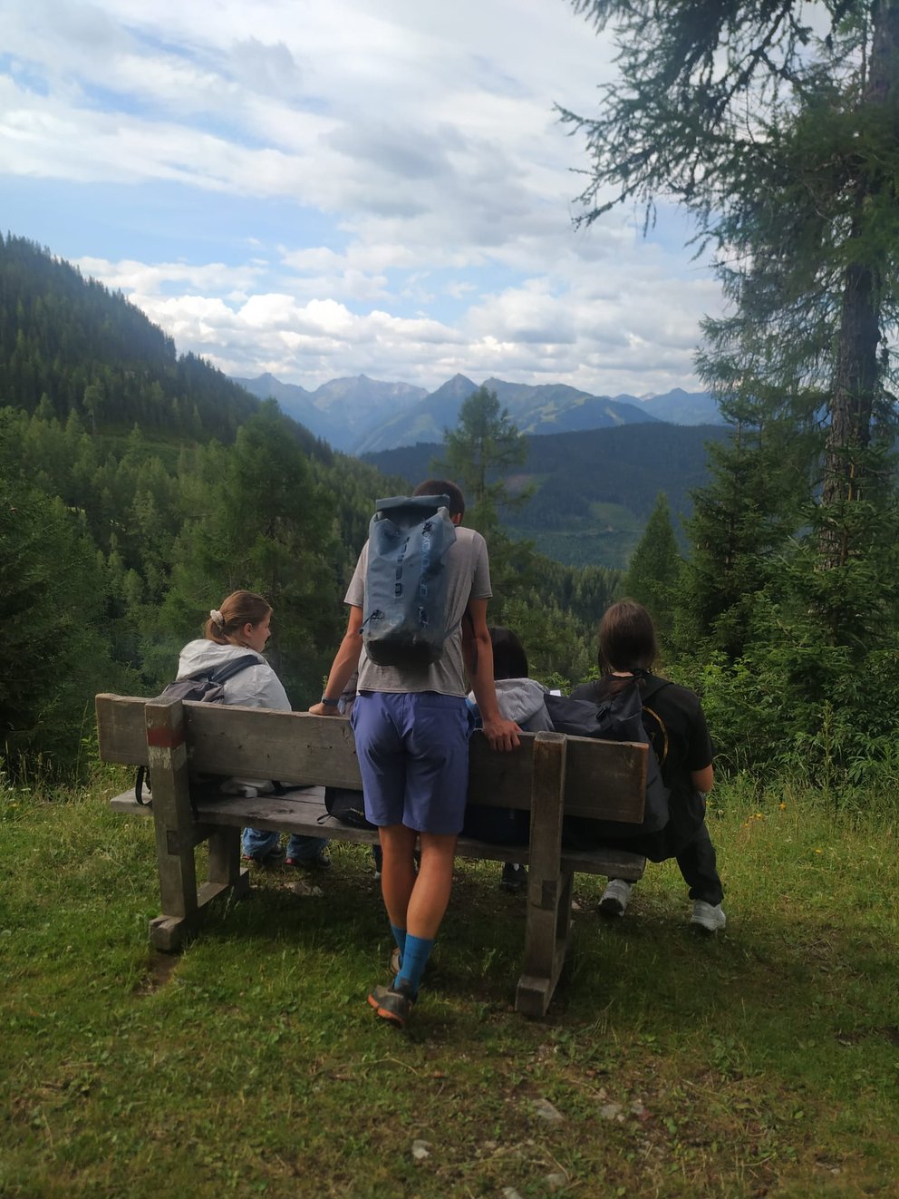 Personengruppe auf einer Sitzbank neben einem Wanderweg