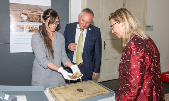 Drei Personen schauen sich wertvolle Objekte aus den historischen Sammlungen der Universitäts- und Landesbibliothek an.