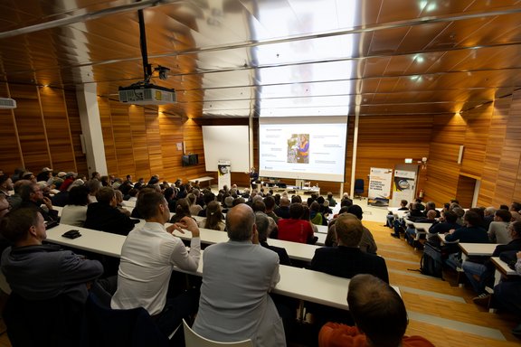 A view from the back into the packed lecture hall.