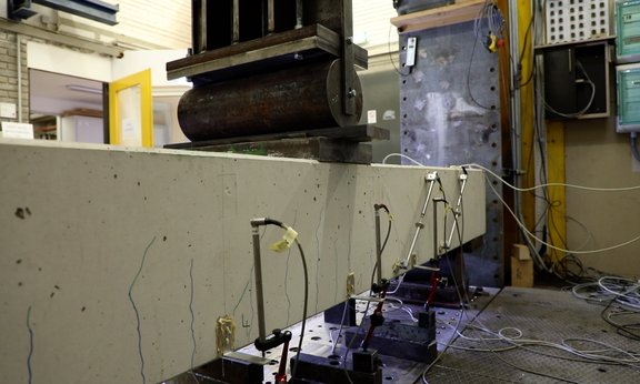 Ein Beton-Balken wird im Experiment mit einer hydraulischen Presse belastet