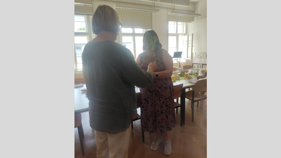 Zu sehen sind die Mitglieder des Instituts beim Sommerumtrunk. Es werden Blumen zum Geburtstag überreicht.