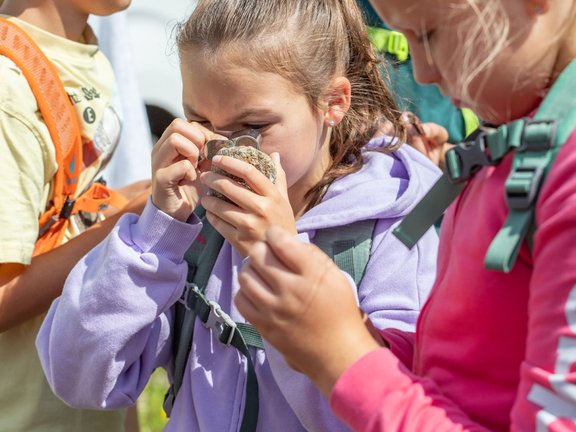 Kind analysier Stein mit Lupe