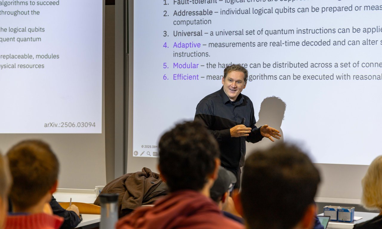 Jay Gambetta vor einer Leinwand, auf der Text zu lesen ist, im Vordergrund Publikum.