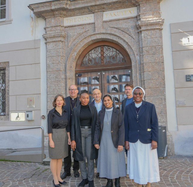 Mehrere Personen stehen vor dem Portal der Theologischen Fakultät