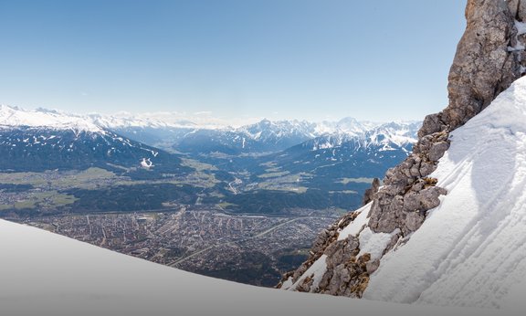 Blick vom Hafelekar Richtung Süden auf die Stadt Innsbruck und das Wipptal. In der Bildmitte die Brennerautobahn mit der Europabrücke, links davon der Patscherkofel mit den beschneiten Skipisten.