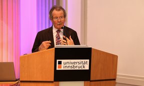 Manfred Nowak an einem Rednerpult mit dem Schriftzug "Universität Innsbruck"
