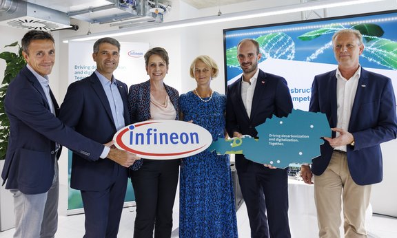 Sechs Personen halten ein Schild mit Schriftzug Infineon und eine Landkarte von Österreich und blicken in die Kamera.
