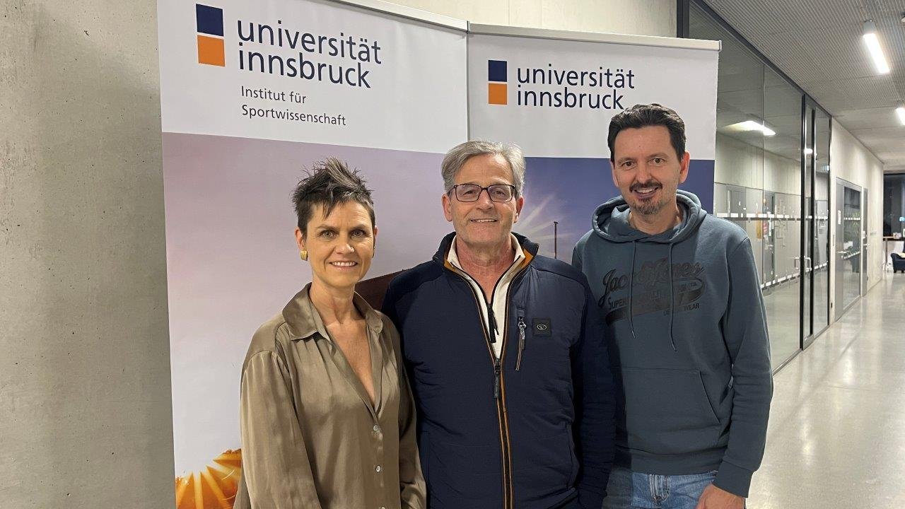 Drei Menschen stehen vor einem Plakat