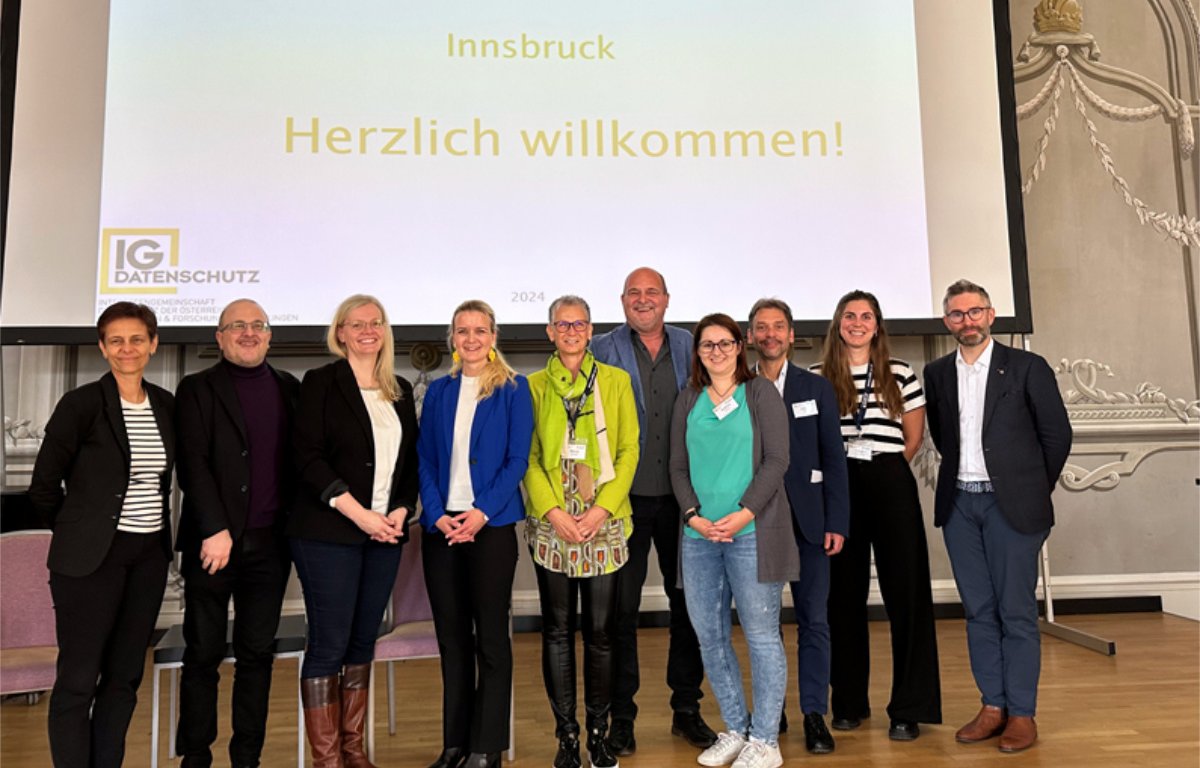 Zehn Personen stehen vor einer Leinwand auf der folgender Text steht: IG Datenschutz, 25.4.-26.4.2024, Innsbruck, Herzlich willkommen!