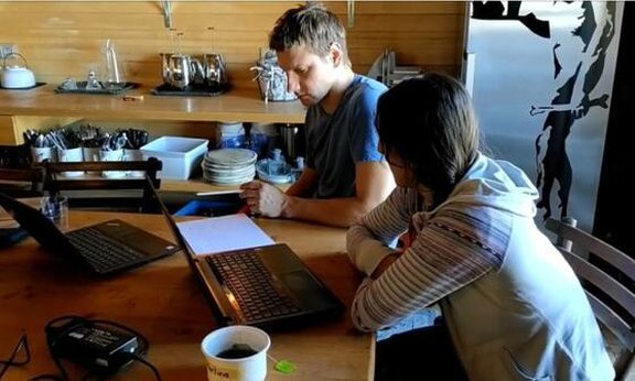 Zwei Personen sitzen an einem Tisch mit Laptops.