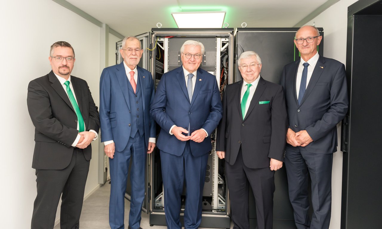 Fünf Personen stehen vor einem AQT-Quantencomputer und blicken in die Kamera