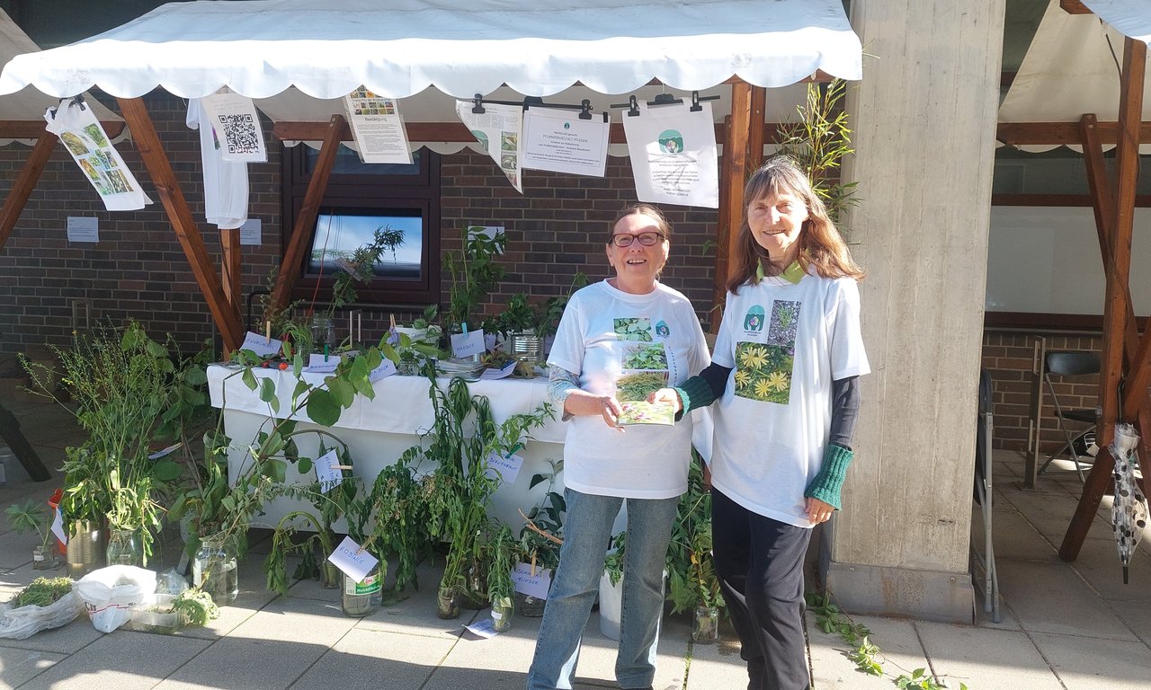 Zwei Personen stehen vor einem Stand mit vielen Pflanzen