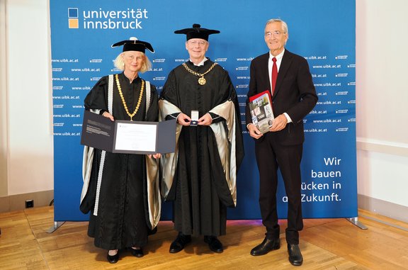 Drei Personen vor einer blauen Pressewand