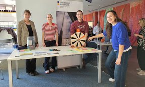 Zu sehen sind Studierende und Mitglieder des Instituts für Praktische Theologie. Sie stehen an einem Informationsstand.