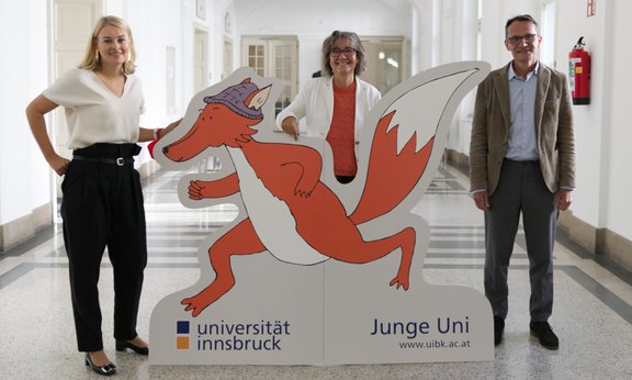 Von links nach rechts: Stadträtin Elisabeth Mayr, Junge Uni-Leiterin Silvia Prock und Vizerektor Bernhard Fügenschuh stehen hinter dem Fuchsmaskottchen der Jungen Uni