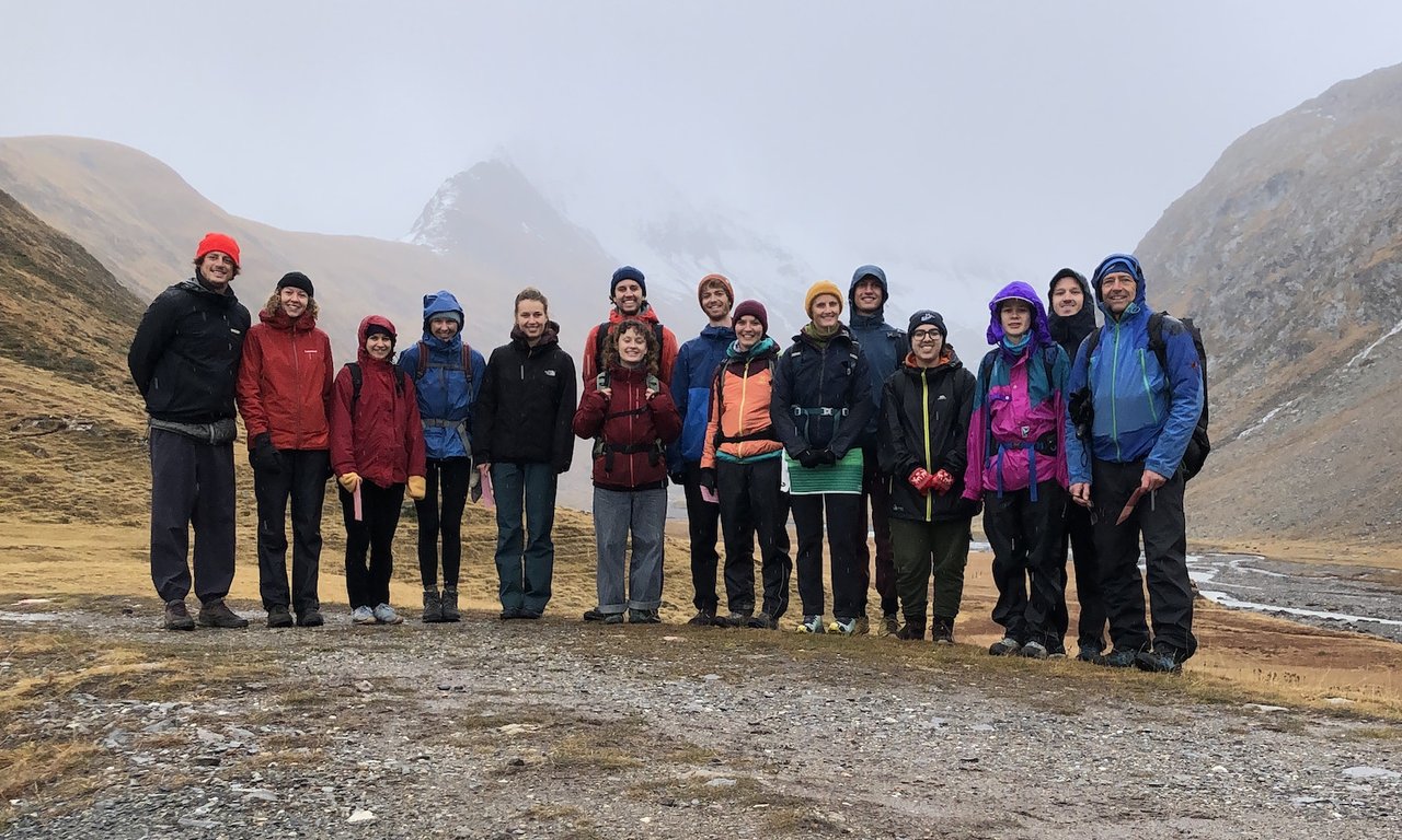 Gruppenfoto im Freien, im Hintergrund Bergkulisse, allerdings bei schlechtem Wetter und Nebel.