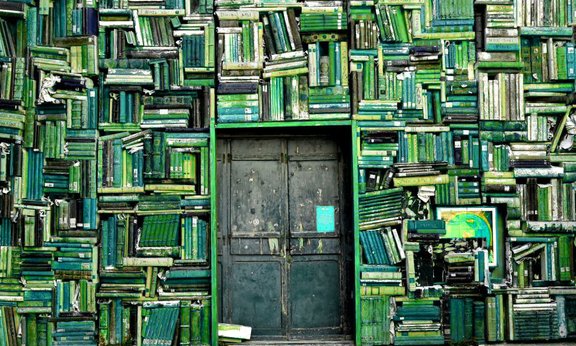 Viele alte Bücher, aufgestapelt um eine schwere Metalltür