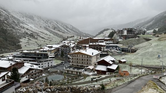 View to a valley of a village with houses and mountains covered in a thin layer of snow